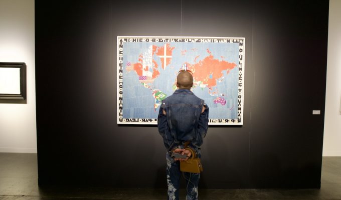 Tariffs and the global art market at Miami Art Week. Visitor views international artwork highlighting cross-border exchange at an art fair.